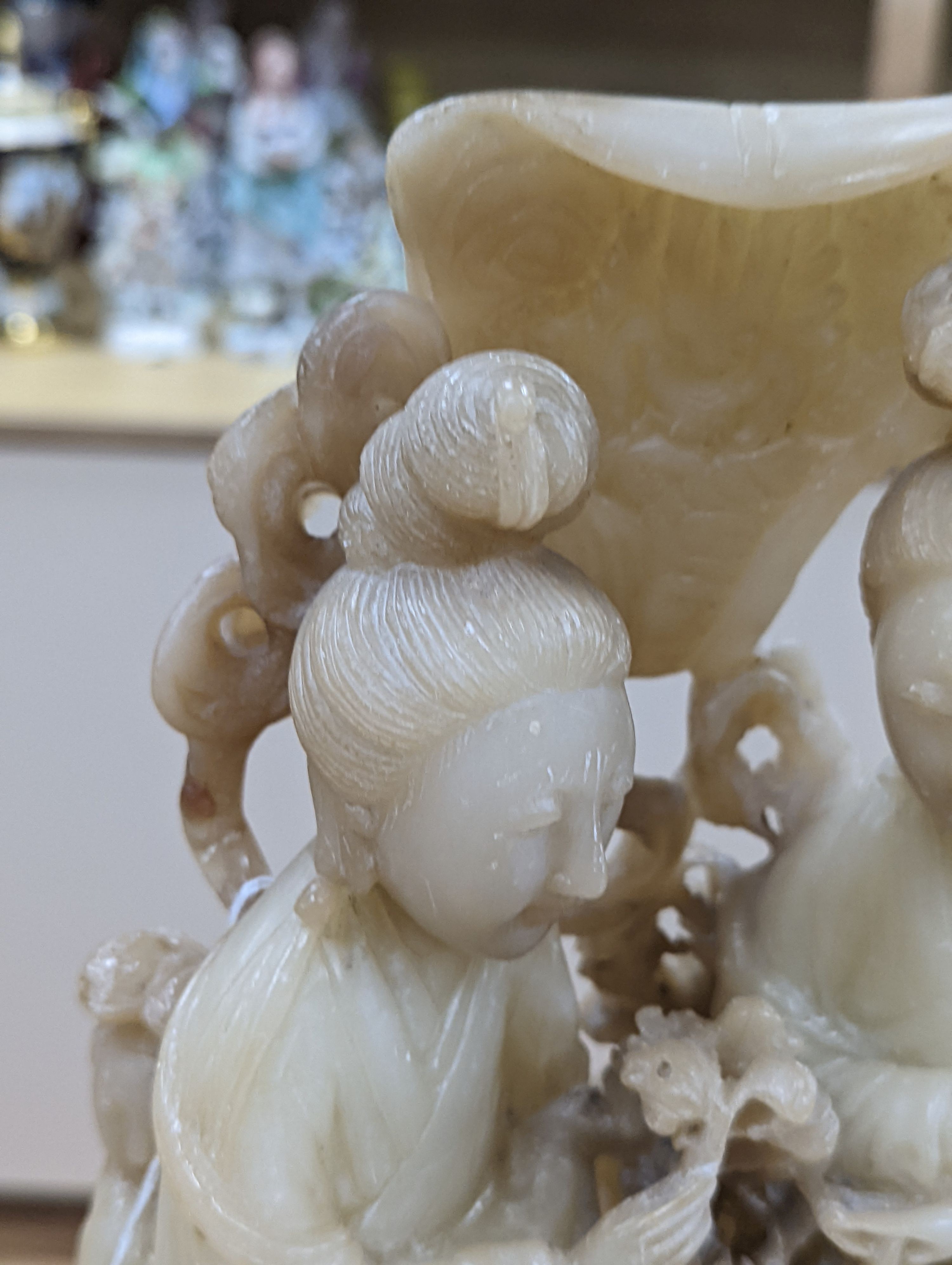 A Chinese soapstone carving of two ladies, wood stand, early 20th century, 36 cms high.